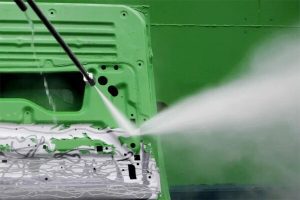 high pressure gun removing green paint from metal